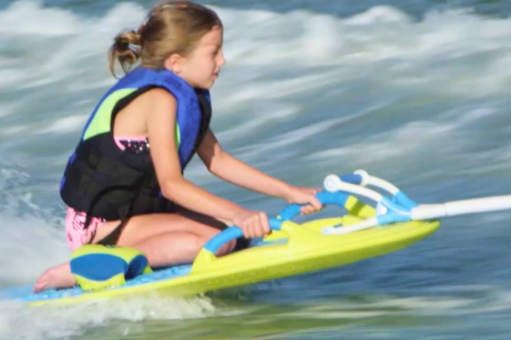 a little girl riding a wave on a surfboard in the water