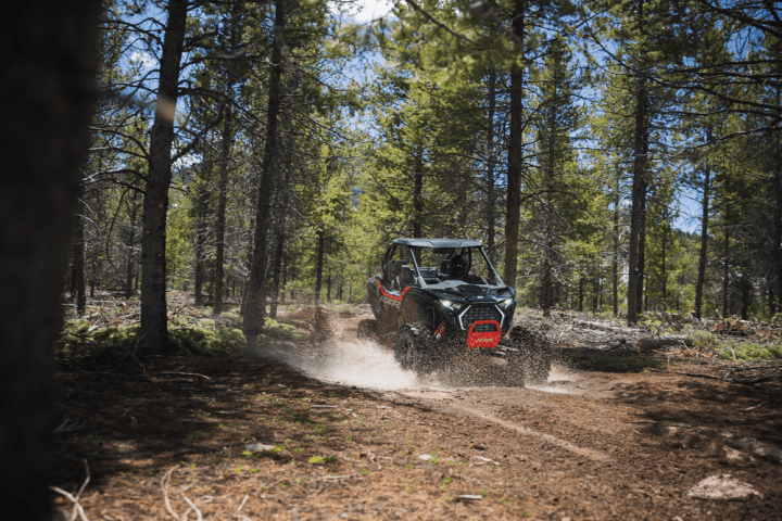 a truck driving down a dirt road in a forest