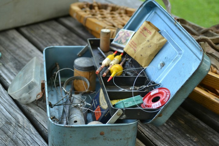 Open blue tackle box with fishing gear on a wooden surface.